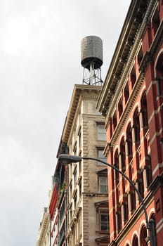 Facades of old houses in Manhattan with a water tank on the roof, New York, USA