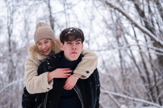 A young couple walks in the park in winter. Guy and girl hugging outdoors