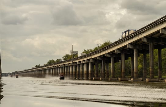 Airboats traveling alongside I-10 interstate bridges over the bayou of Atchafalaya basin near Baton Rouge Louisiana