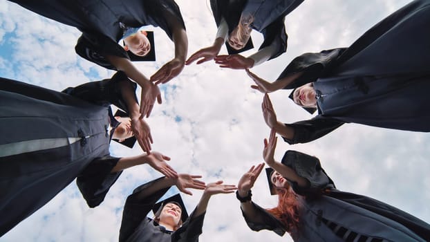 College graduates make a circle of their hands