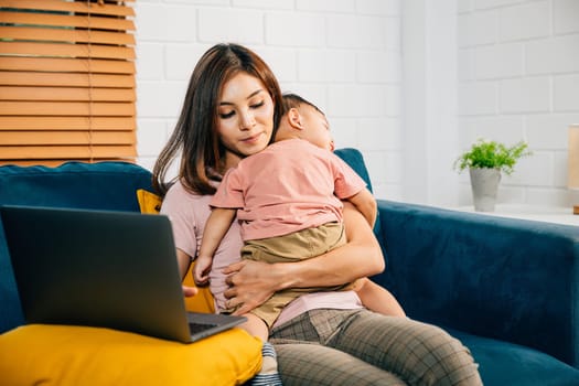 Balancing motherhood and work a businesswoman types on her laptop as her baby daughter peacefully naps on the sofa. This portrait captures their loving bond.