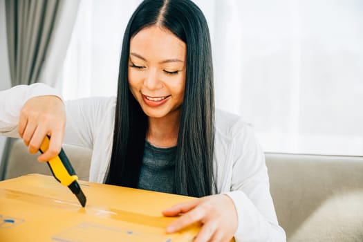 Woman uses a utility cutter for precision unboxing of online shopping cardboard box contents. Engaged in opening unpacking and discovering. Retail and surprise concept.