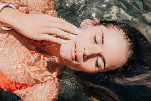 Side view a Young beautiful sensual woman in a mint long dress posing on a volcanic rock high above the sea during sunset. Girl on the nature on overcast sky background. Fashion photo