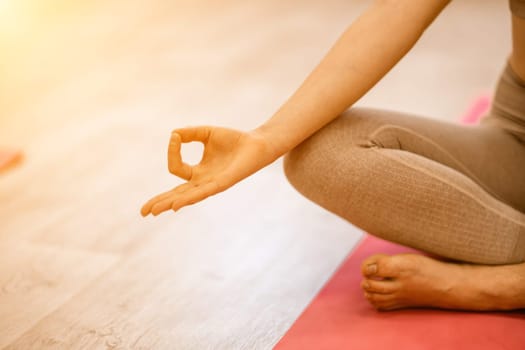 Girl does yoga. Young woman practices asanas on a beige one-ton background