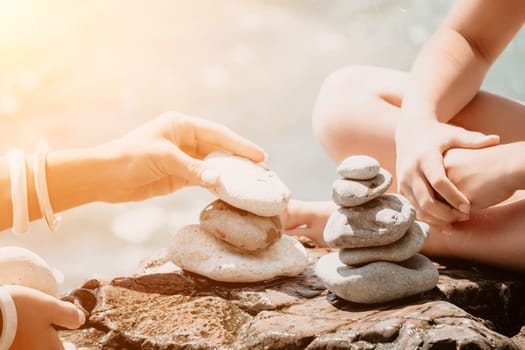 Balanced Pebbles Pyramid on the Beach on Sunny Day and Clear Sky at Sunset. Blue Sea on Background Selective focus, zen stones on sea beach, meditation, spa, harmony, calm, balance concept.