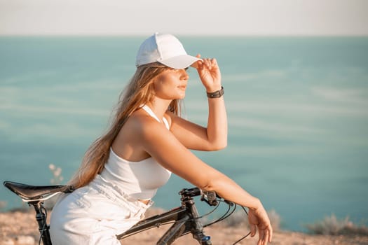 A woman cyclist on a mountain bike looking at the landscape sea. Adventure travel on bike