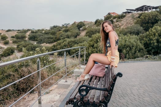 Woman travel sea. Happy tourist taking picture outdoors for memories. Woman traveler looks at the edge of the cliff on the sea bay of mountains, sharing travel adventure journey.