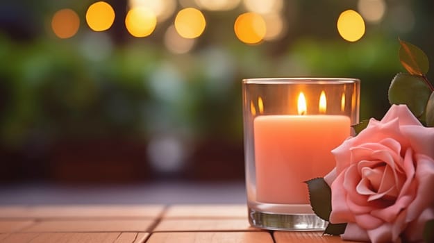 A burning candle and rose flowers against the background of a garden. Banner with copy space. Self care and aromatherapy concept. High quality photo