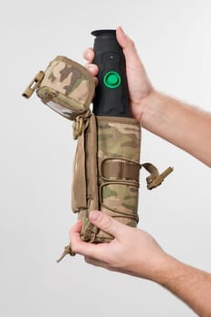 Military monocular in a case for storage and carrying, a man demonstrates a monocular in a protective case to a bag in pixels.