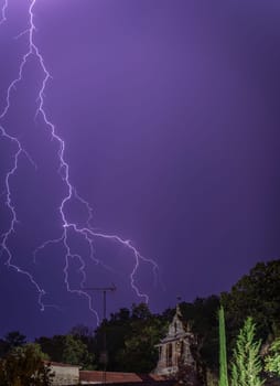 Dramatic lightning bolt lights up the sky over an ancient building at night.