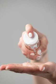 cosmetologist squeezes cream from a jar on the hand, hand and face skin care.