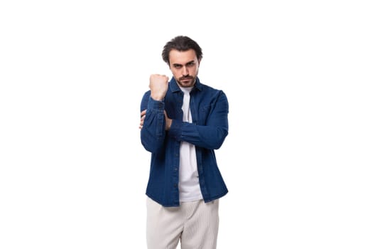 young serious handsome brutal brunette guy in a denim shirt and light-colored trousers.