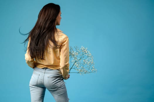 Portrait of a girl on a blue background with her back turned, a brunette girl with long hair.