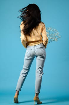 Portrait of a girl on a blue background with her back turned, a brunette girl with long hair.