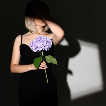 portrait of a blonde girl with shadows and a hydrangea flower in her hands, a romantic portrait of a girl.