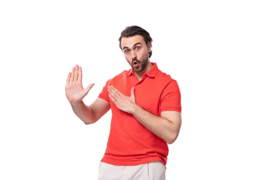 young brutal man with black hair and a beard dressed in a red t-shirt with a mockup for printing on a white background with copy space.