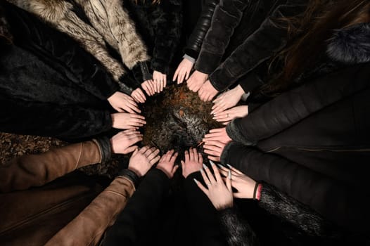 children's hands are folded with palms up in a circle, hands are held over the fire.