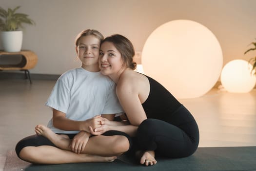 portrait of a mother and daughter of a teenager in sports clothes hugging, who are together in a fitness room. the concept of family sports.