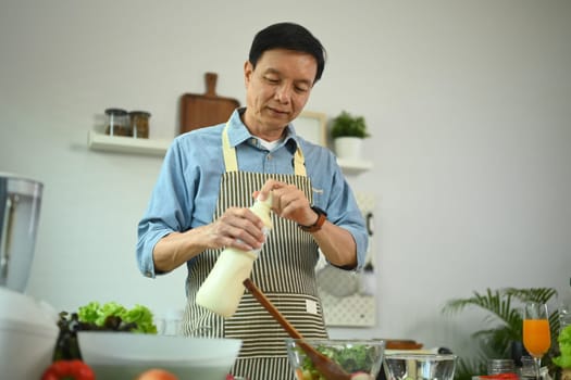 Portrait of senior man cooking healthy food at kitchen. Healthy lifestyle concept.