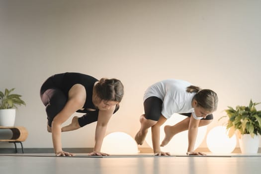 Mom and teenage daughter do gymnastics together in the fitness room. A woman and a girl train in the gym.