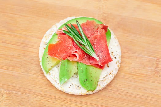 Rice Cake Sandwich with Fresh Avocado, Jamon and Rosemary on Bamboo Cutting Board. Easy Breakfast. Diet Food. Quick and Healthy Sandwiches. Crispbread with Tasty Filling. Healthy Dietary Snack