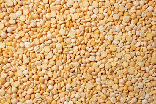 Uncooked Polished Split Peas Background. A Culinary Canvas of Dry Yellow Peas, Creating a Lively and Textured Background for Gourmet Cooking. Scattered Raw Polished Peas. Healthy Eating Ingredients