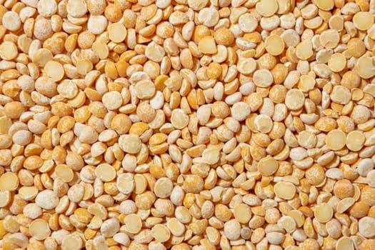 Uncooked Polished Split Peas Background. A Culinary Canvas of Dry Yellow Peas, Creating a Lively and Textured Background for Gourmet Cooking. Scattered Raw Polished Peas. Healthy Eating Ingredients