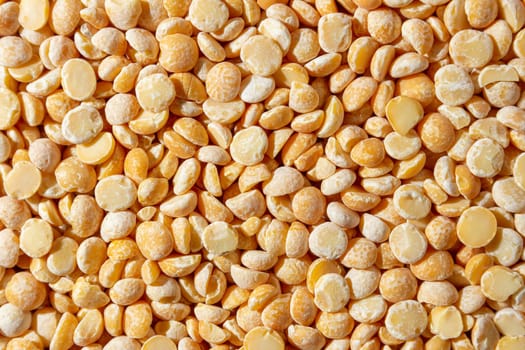 Uncooked Polished Split Peas Background. A Culinary Canvas of Dry Yellow Peas, Creating a Lively and Textured Background for Gourmet Cooking. Scattered Raw Polished Peas. Healthy Eating Ingredients