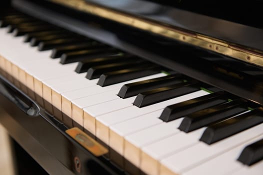 Close up shot of black wooden vintage grand piano keyboard, with black and white keys. Still life. Classic musical chord instrument