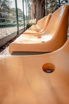 Close up yellow seats of tribune in public park concept photo. Chairs for audience in park. Cultural environment concept. Empty seats, modern stadium. High quality picture for wallpaper