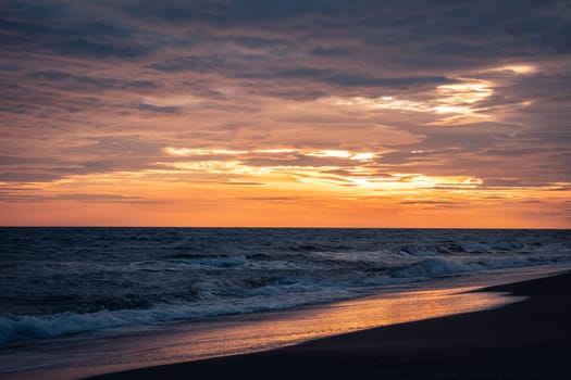 Wet surfline of black beach landscape photo. Beautiful nature scenery photography with bright sky on background. Idyllic sunset scene. High quality picture for wallpaper, travel blog, magazine, article