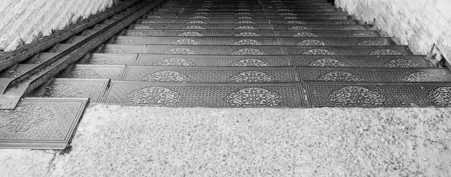 Ornate steel plate underground staircase concept photo. Metal floor plate, rusted steel plate. District of European town. High quality picture for wallpaper. Suitable for background images and abstract illustrations.