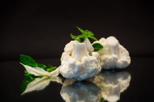 slices of raw small raw cauliflower isolated on black background