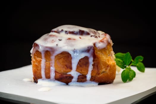 cooked baked sweet Cinnabon with cream isolated on black background