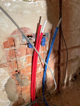 Red and blue corrugated pipes with wires come out of a a plasterboard wall. Distribution of wiring during repairs. Overheating of wires and cooling.High speed data transfer High quality photo