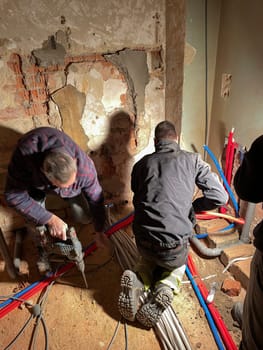 team of professional electricians is working at the construction site,operation specialists are installing wiring in the house inside the walls, High quality photo