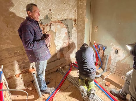 team of professional electricians is working at the construction site,operation specialists are installing wiring in the house inside the walls, High quality photo