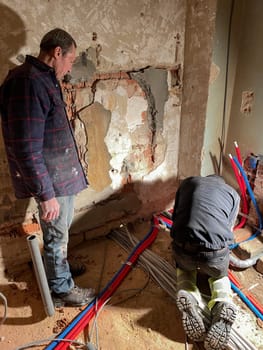 team of professional electricians is working at the construction site,operation specialists are installing wiring in the house inside the walls, High quality photo