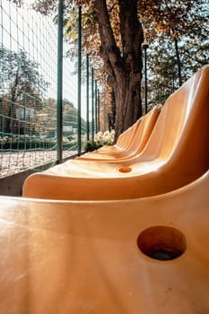 Close up yellow seats of tribune on sport stadium concept photo. Chairs for audience in park. Cultural environment concept. Empty seats, modern stadium.