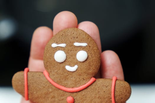 Person holding a gingerbread man. Close-up, selective focus, Christmas