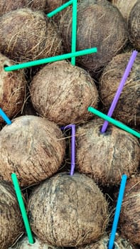 Background of coconut with plastic drinking tubes, vertical frame.