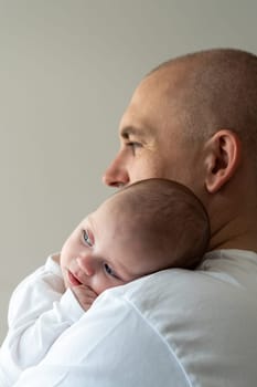 A newborn baby lies on his father's shoulder. Close-up. Caring concept.