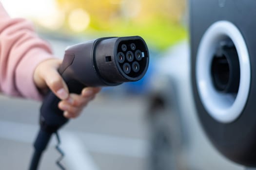 The girl took off the gas nozzle to charge an electric car. High quality photo