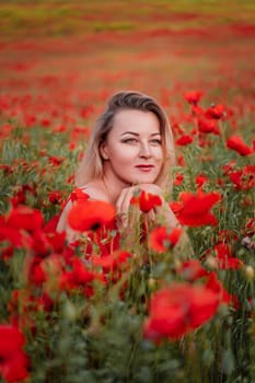 Happy woman in a red dress in a beautiful large poppy field. Blond sits in a red dress, posing on a large field of red poppies.