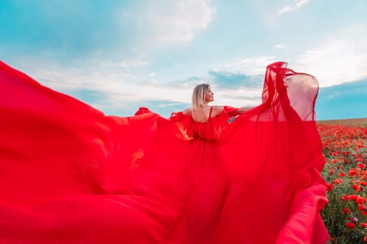 Woman poppy field red dress. Happy woman in a long red dress in a beautiful large poppy field. Blond stands with her back posing on a large field of red poppie