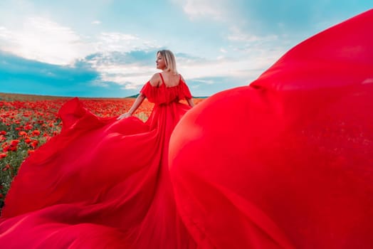 Woman poppy field red dress. Happy woman in a long red dress in a beautiful large poppy field. Blond stands with her back posing on a large field of red poppie