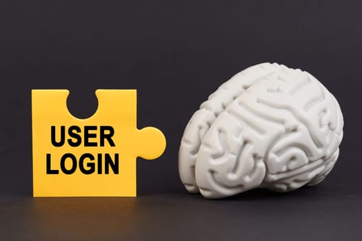 On a black surface there is a brain and a yellow puzzle with the inscription - User login. Business and technology concept.