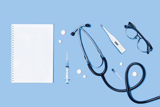 Medical blue background with different accessories: stethoscope, syringe and tablets.