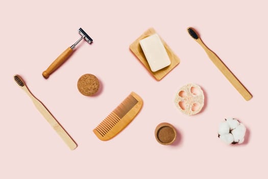 Bathroom accessories on pink background. Natural bamboo toothbrush, sponges, cotton flowers, shaving brush. Flat lay, top view.