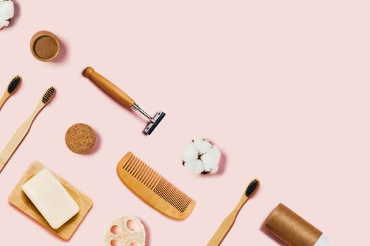 Bathroom accessories on pink background. Natural bamboo toothbrush, sponges, cotton flowers, shaving brush. Flat lay, top view.